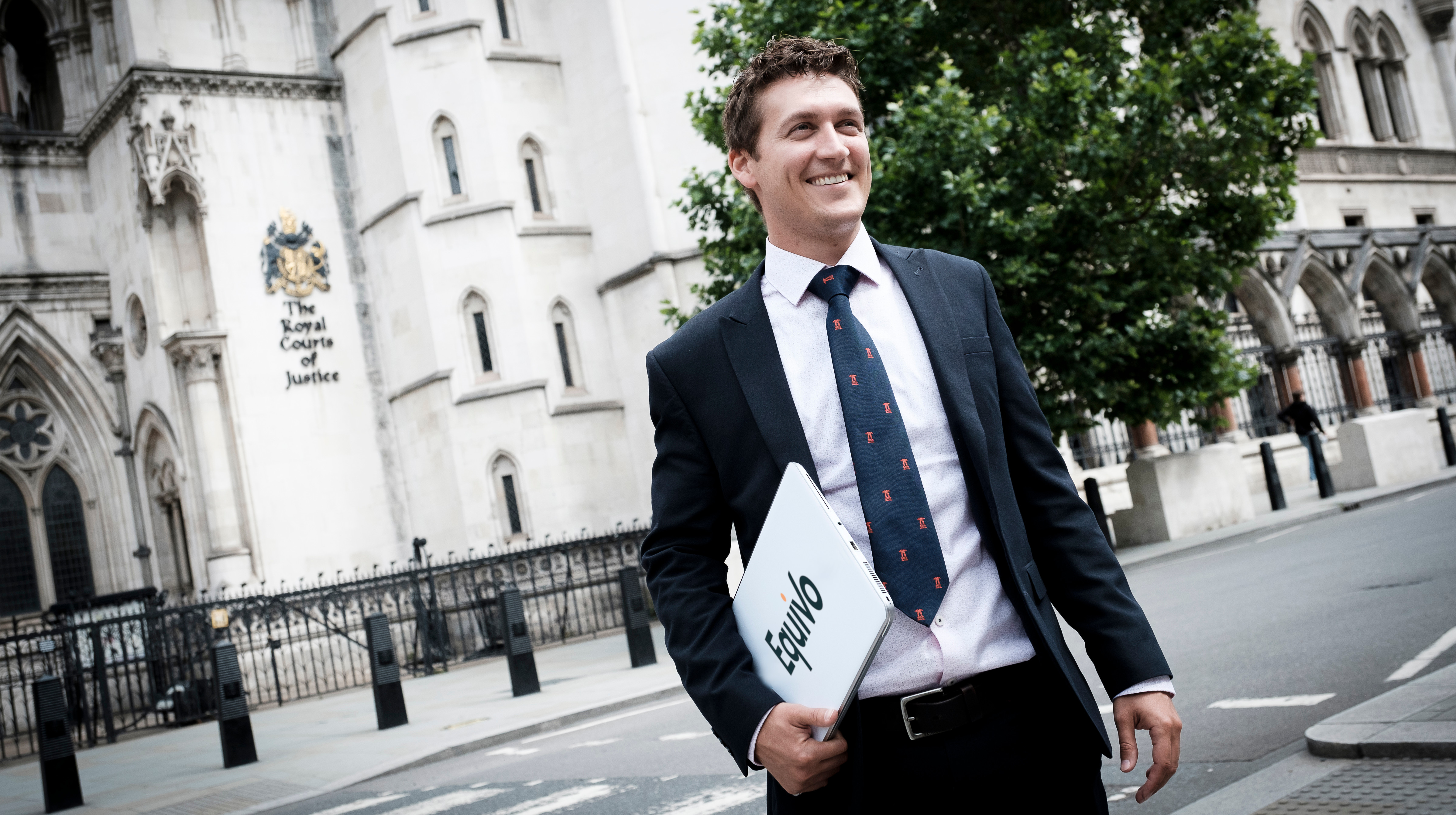 Equivo High Court enforcement specialist outside the High Court in London, holding a laptop.