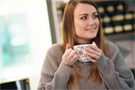 A female customer of Equivo holding a cup of tea, smiling