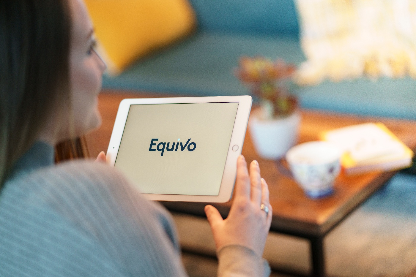 A female customer of Equivo feeling positive from using a tablet to resolve her delinquent debt on the Equivo website.