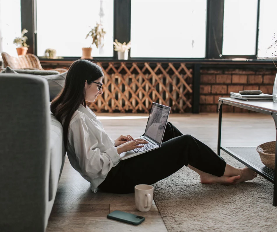 Woman with laptop sat on the floor, enlisting the services of Equivo: one of the UK's premier debt collection companies