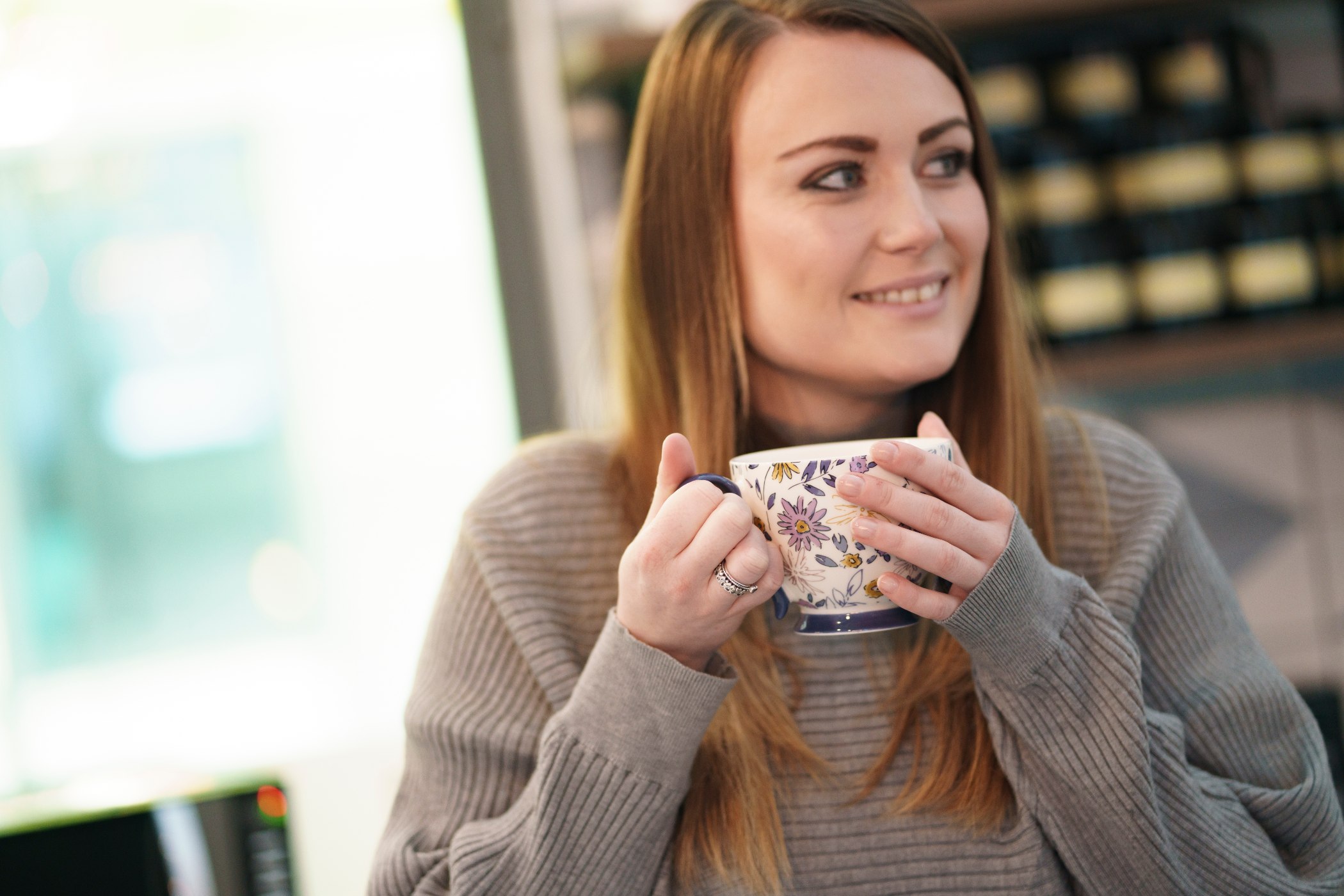 A female customer of Equivo holding a cup of tea, looking positive after a debt settlement plan resolves her delinquent debt.